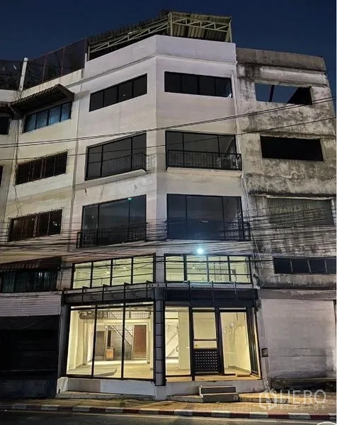 店屋 出租在Suan Luang, Bangkok - 多层商住楼夜景外立面，底层宽玻璃门面，上层大窗户。