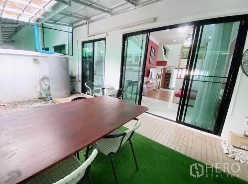 Townhouse for rent in Wang Thonglang, Bangkok - Covered patio with artificial grass, outdoor dining set, and large sliding doors.