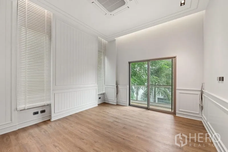 บ้าน ขาย - ห้องนอนผนังบัวสีขาว พื้นไม้ และประตูกระจกออกระเบียง