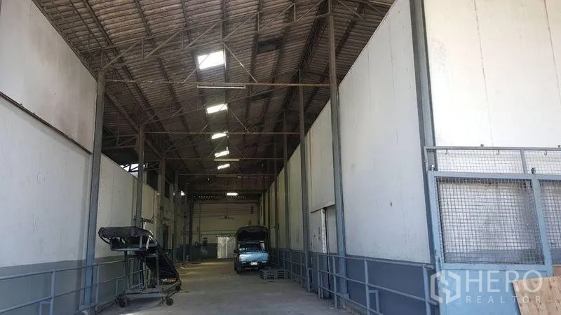 คลังสินค้า ให้เช่าในPathum Thani - ลานโหลดสินค้ามีหลังคา โครงเหล็ก ทางลาด และรถบรรทุกภายในโกดัง