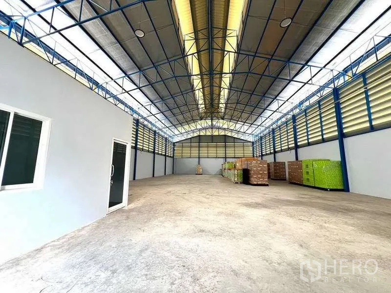 Warehouse for rent in Lat Lum Kaeo, Pathum Thani - Spacious warehouse hall with high ceiling and pallets stacked along the wall.