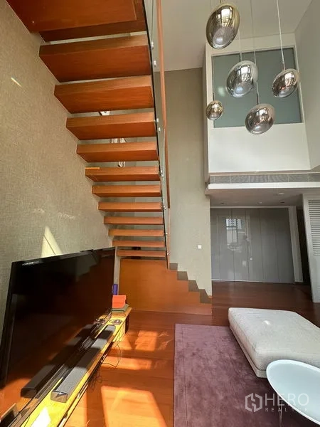 Condominium for rent or sale in Sathon, Bangkok - Detail of cantilevered wooden staircase with chrome pendant light cluster.