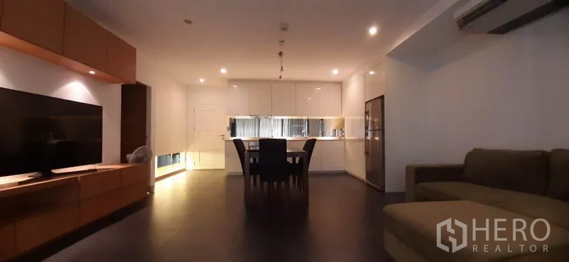 คอนโด ให้เช่าในPhaya Thai, Bangkok - ห้องนั่งเล่นแบบโอเพ่นสเปซ มีโซฟา ชุดทีวี และครัวโทนขาวด้านหลังพร้อมไฟดาวน์ไลท์