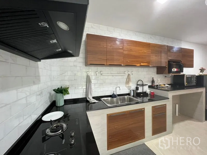 ทาวน์เฮาส์ ให้เช่า - ครัวบิลท์อินพร้อมเตาแก๊ส เครื่องดูดควัน ท็อปหินสีดำ และตู้ไม้