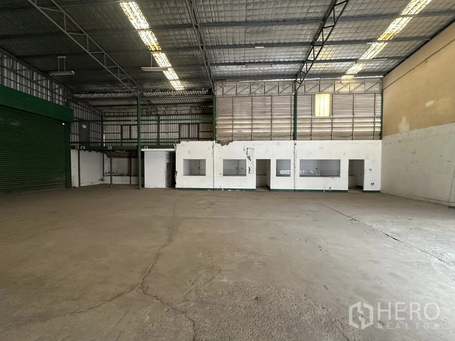 Warehouse for rent in Suan Luang, Bangkok - Clear-span floor facing a mezzanine structure and multiple office cut-outs along the wall.