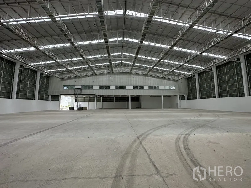 โรงงาน ให้เช่าในPathum Thani - พื้นโรงงานมีรอยยาง หันหน้าไปยังชั้นลอยสำนักงานและช่องโหลดสินค้า