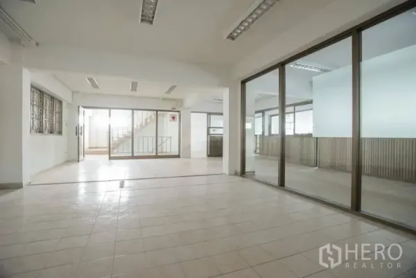 店屋 出租在Wang Thonglang, Bangkok - 一层开放式空间，瓷砖地面，玻璃隔间，后方有通往楼上的楼梯。