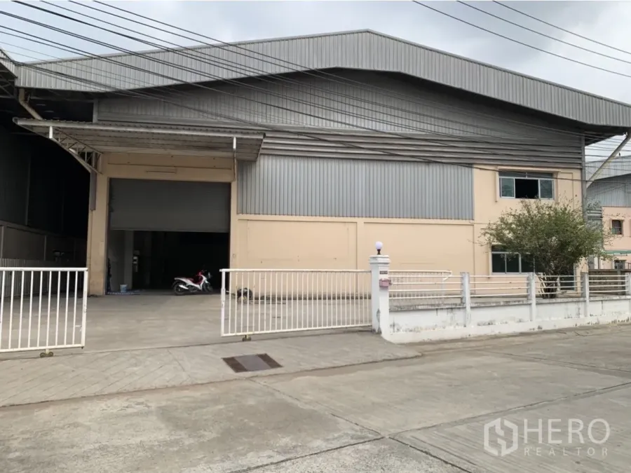 โรงงาน ให้เช่าในMueang Samut Prakan, Samut Prakan - ด้านหน้าโรงงานโครงเหล็ก ผนังเมทัลชีต พร้อมประตูรั้วและทางเข้ากว้าง