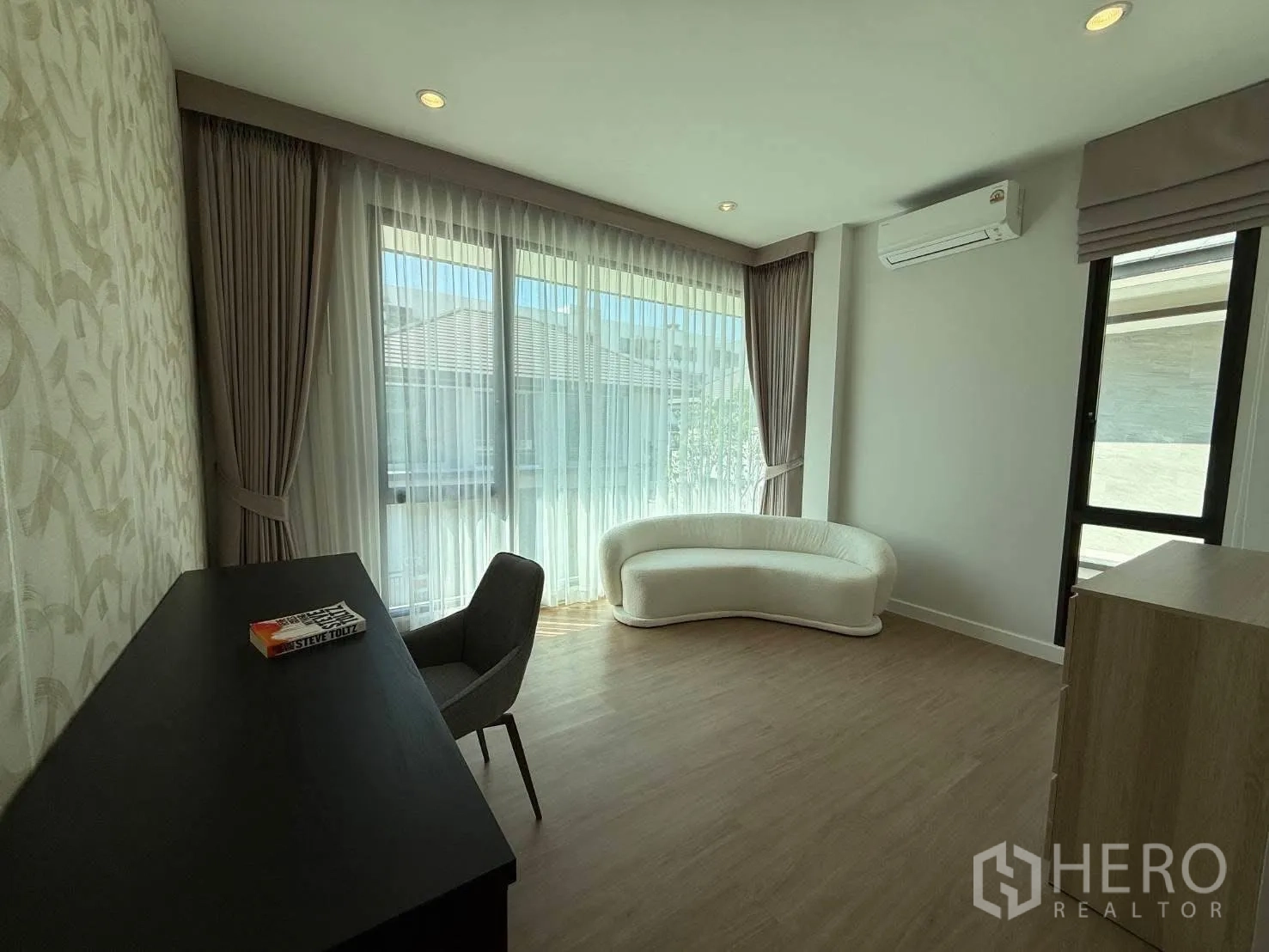 Detached House for rent in Bang Phli, Samut Prakan - Spacious room with desk, chair, curved sofa, air conditioner, and large windows.