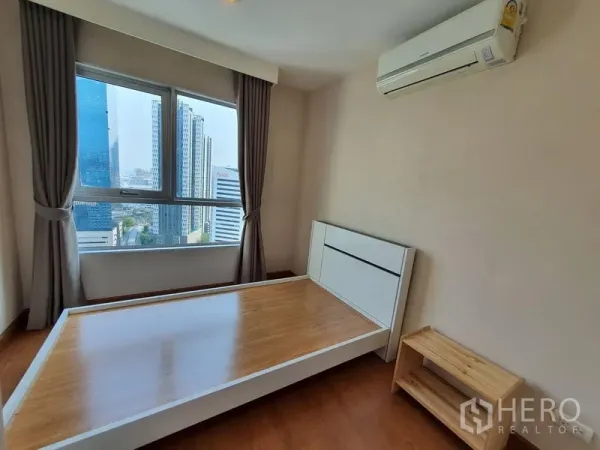 Condominium for rent in Huai Khwang, Bangkok - Second bedroom with city-view window, air conditioner and wood bedframe in Huai Khwang, Bangkok.