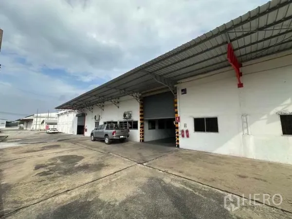 货栈 出租在Mueang Pathum Thani, Pathum Thani - 仓库正立面，带雨棚、停车硬化地与消防设备。