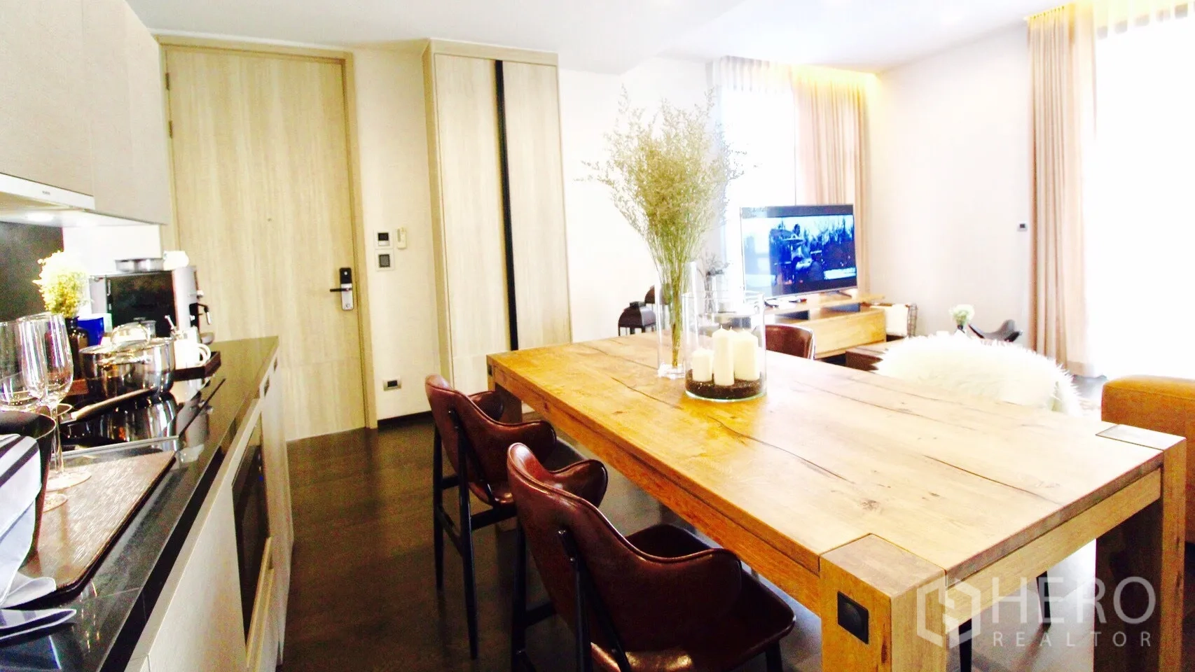 Condominium for rent or sale in Watthana, Bangkok - Open-plan kitchen and dining area with a solid wood table, leather chairs, and built-in cabinets in a bright condo.