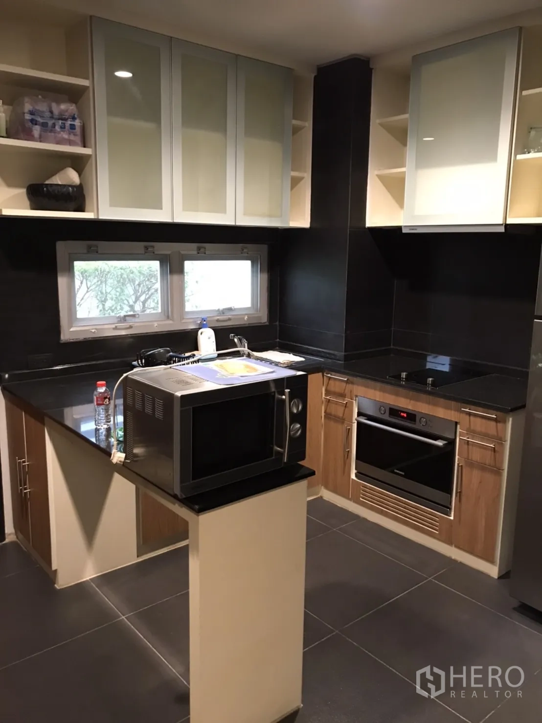Detached House for rent in Wang Thonglang, Bangkok - U-shaped kitchen with black granite counters, built-in oven, microwave and glass-front cabinets