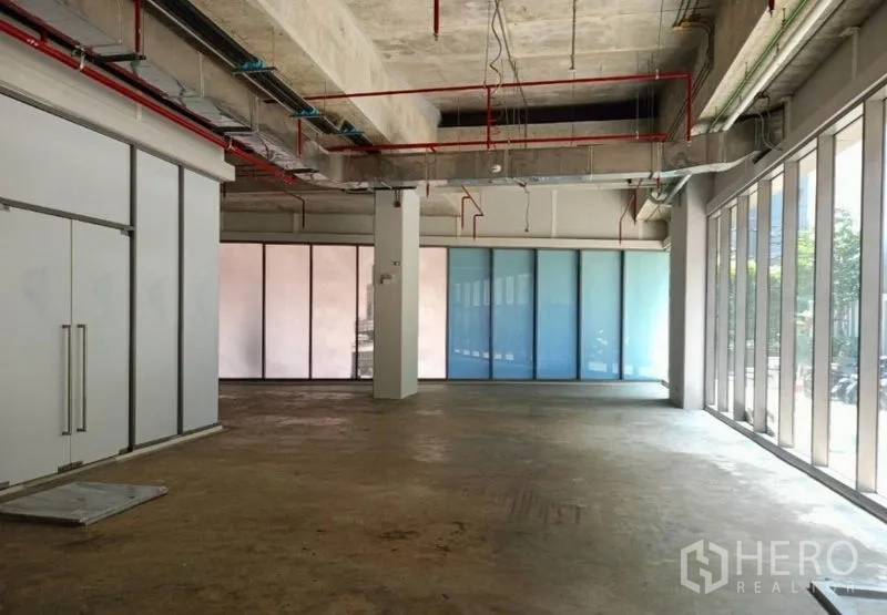 零售空间 出租在Watthana, Bangkok - 店铺另一角度：中央立柱、双开门入口与磨砂玻璃墙，自然采光充足