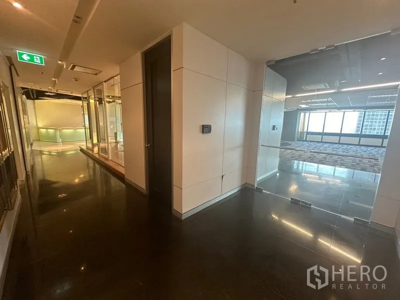 Office Space for rent in Khlong Toei, Bangkok - Corridor with glass walls leading to a bright office space with large windows.