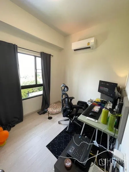 Condominium for sale in Sathon, Bangkok - Compact home office with a large window, desk setup, ergonomic chair and wall-mounted AC.
