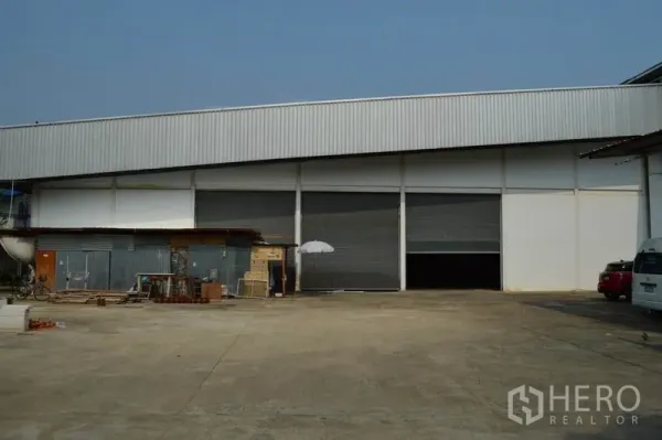 Warehouse for rent in Bang Sue, Bangkok - Industrial warehouse exterior in Bang Sue, Bangkok with multiple roller shutter bays and a wide concrete yard.