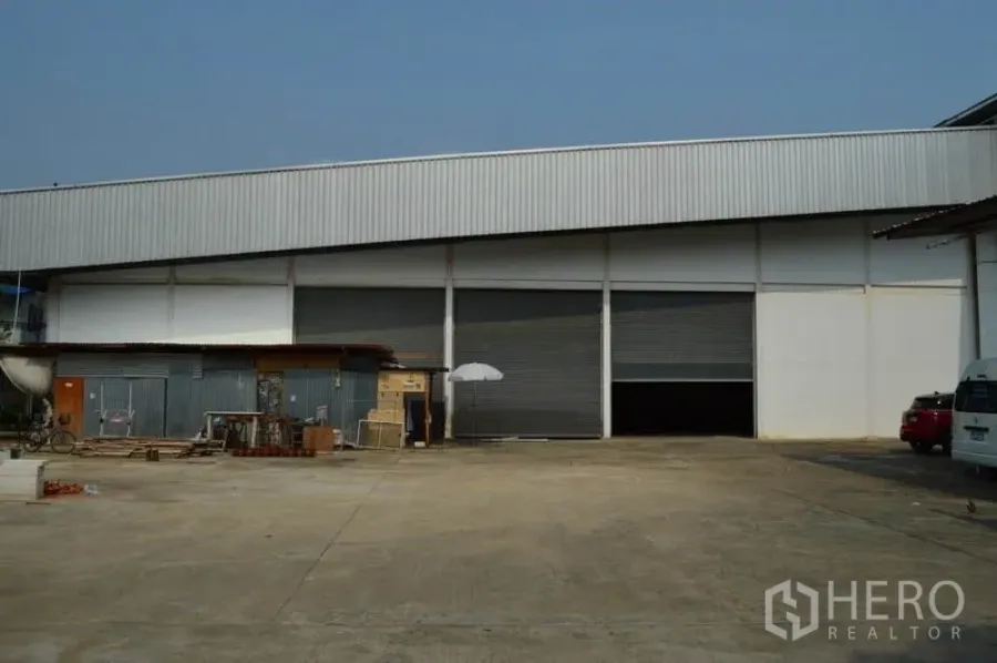 Warehouse for rent in Bang Sue, Bangkok - Industrial warehouse exterior in Bang Sue, Bangkok with multiple roller shutter bays and a wide concrete yard.