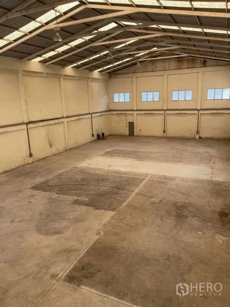 货栈 出租在Samut Sakhon - 宽跨仓库视角，钢桁架屋顶、吊灯与开阔作业区。