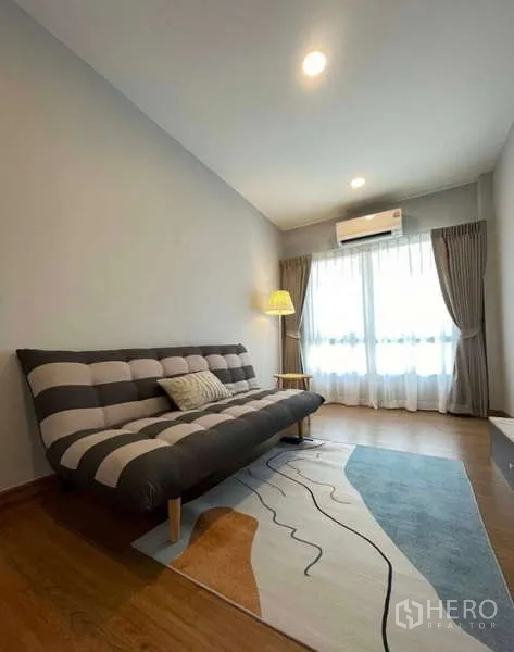 Detached House for rent in Bang Phli, Samut Prakan - Cozy lounge room with striped sofa bed, floor lamp and sliding doors to a balcony