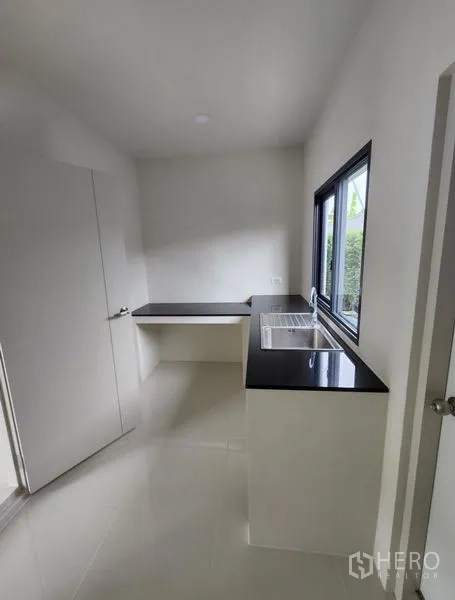 Detached House for rent in Bang Phli, Samut Prakan - Built-in kitchen with black countertop, sink by the window and storage space.