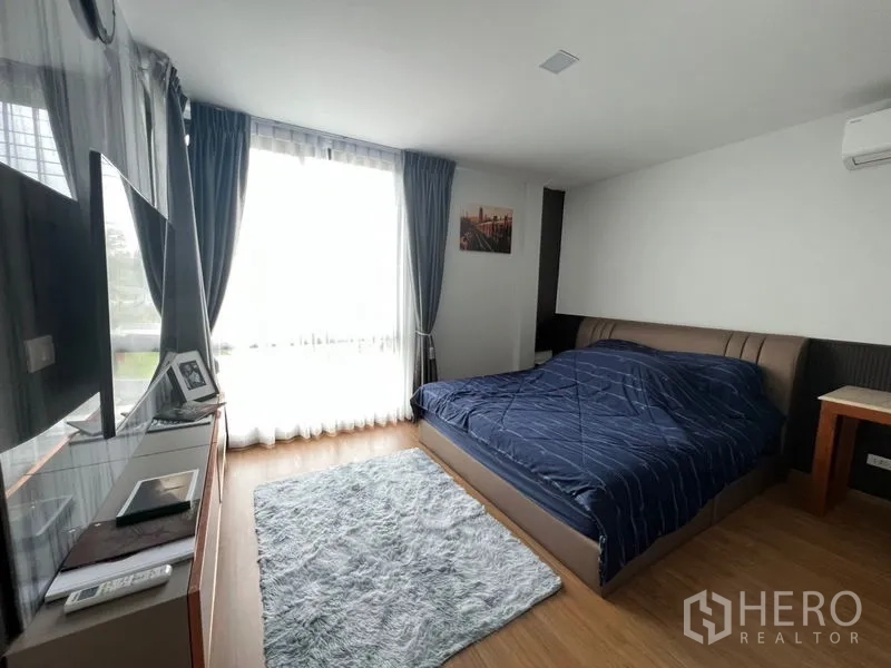 ทาวน์เฮาส์ ให้เช่า - ห้องนอนมาสเตอร์สว่างไสว หน้าต่างบานใหญ่ ชุดเครื่องนอนสีน้ำเงิน และพรม