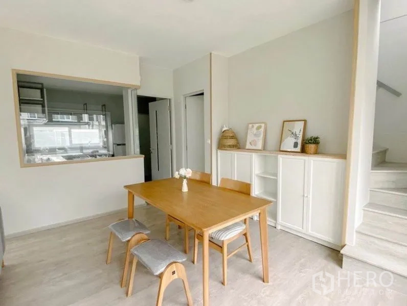 独立式住宅 出租在Prawet, Bangkok - 餐区木质餐桌，旁连带传菜窗的厨房