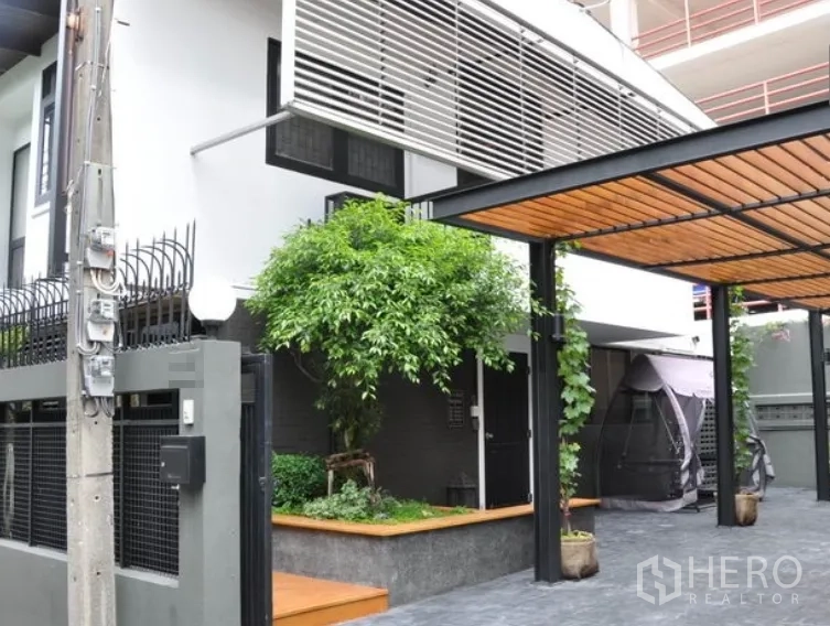 บ้าน ให้เช่าในWatthana, Bangkok - บ้านเดี่ยวสองชั้นสไตล์โมเดิร์น มีระแนงบังแดด ที่จอดรถมีหลังคา และสวนเล็กๆ