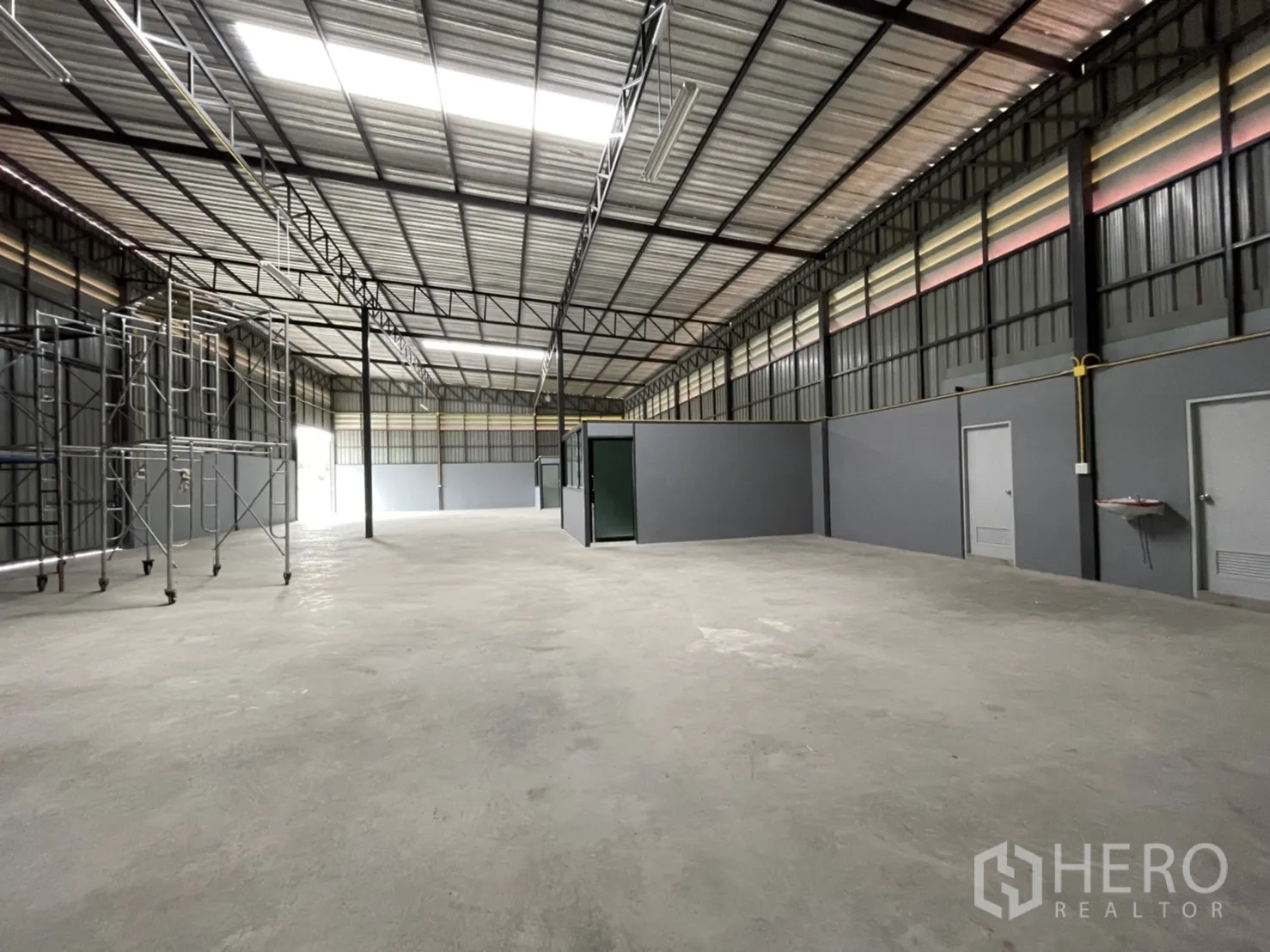 工厂 出租在Khlong Luang, Pathum Thani - 纵深视角的厂房空间，左侧有移动脚手架，中部为玻璃办公室。