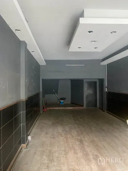 店屋 出租在Watthana, Bangkok - 一层临街营业空间，深进深，吊顶嵌灯与深色墙面，通向后室