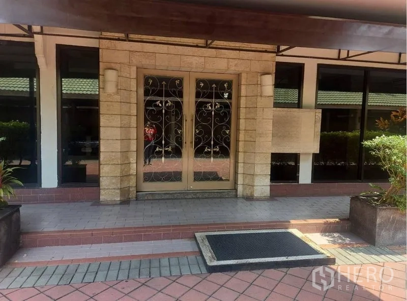 零售空间 出租在Pathum Wan, Bangkok - 建筑入口，双开玻璃门配铁艺装饰与石材立面。