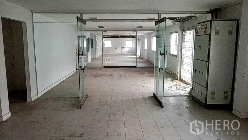 Warehouse for rent in Nakhon Pathom - Office zone with glass double doors and electrical control cabinets inside the facility.