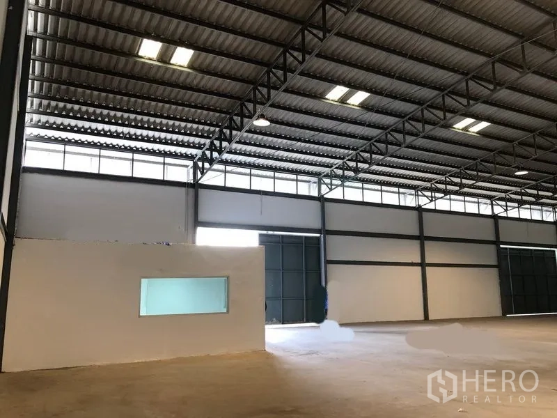 คลังสินค้า ให้เช่าในKhlong Luang, Pathum Thani - ด้านข้างอาคารโกดัง ประตูสไลด์ขนาดใหญ่ และลานคอนกรีตสำหรับขนถ่าย.
