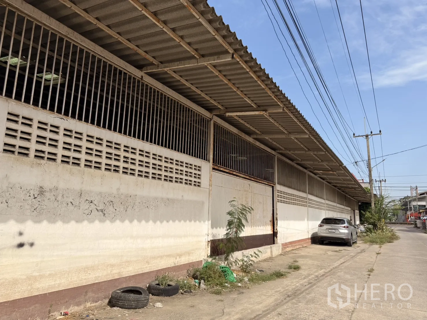 Warehouse for rent in Lam Luk Ka, Pathum Thani - Side elevation of the warehouse with louvered vents and protective grilles.