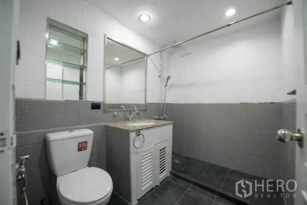 公寓 出租在Khlong Toei, Bangkok - 现代卫浴，超大镜面、洗手台、坐便器与深色地砖的步入式淋浴区。