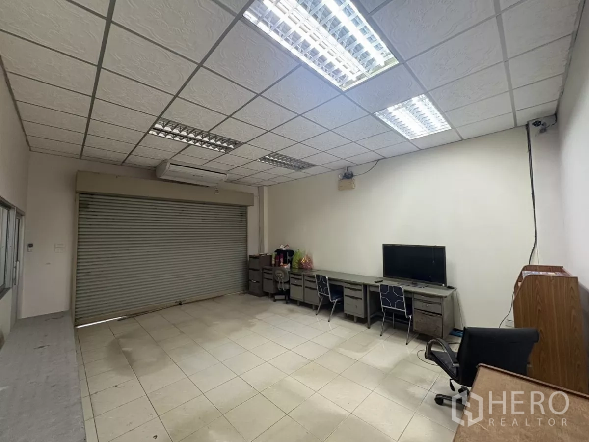 คลังสินค้า ให้เช่าในBang Phli, Samut Prakan - ออฟฟิศชั้นล่าง มีประตูม้วน โต๊ะทำงาน และเครื่องปรับอากาศ