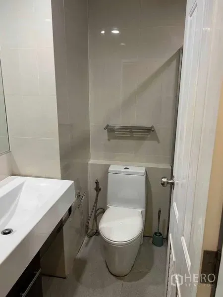 公寓 出售在Bang Na, Bangkok - 紧凑卫浴，坐便器、手持喷枪与现代洗手台。