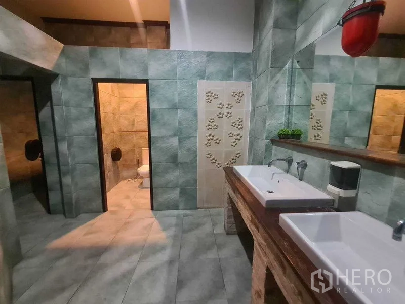 พื้นที่ขายปลีก ให้เช่าในWatthana, Bangkok - ห้องน้ำปูกระเบื้องสีเขียว มีอ่างล้างหน้าทรงเหลี่ยมคู่ กระจกบานยาว และห้องส้วมสองห้อง