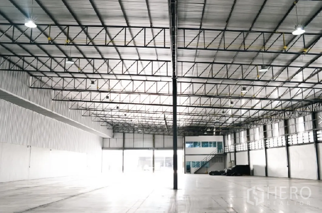 Factory for rent in Si Racha, Chon Buri - Spacious interior with high metal truss roof, bright high-bay lights, and polished concrete floor.