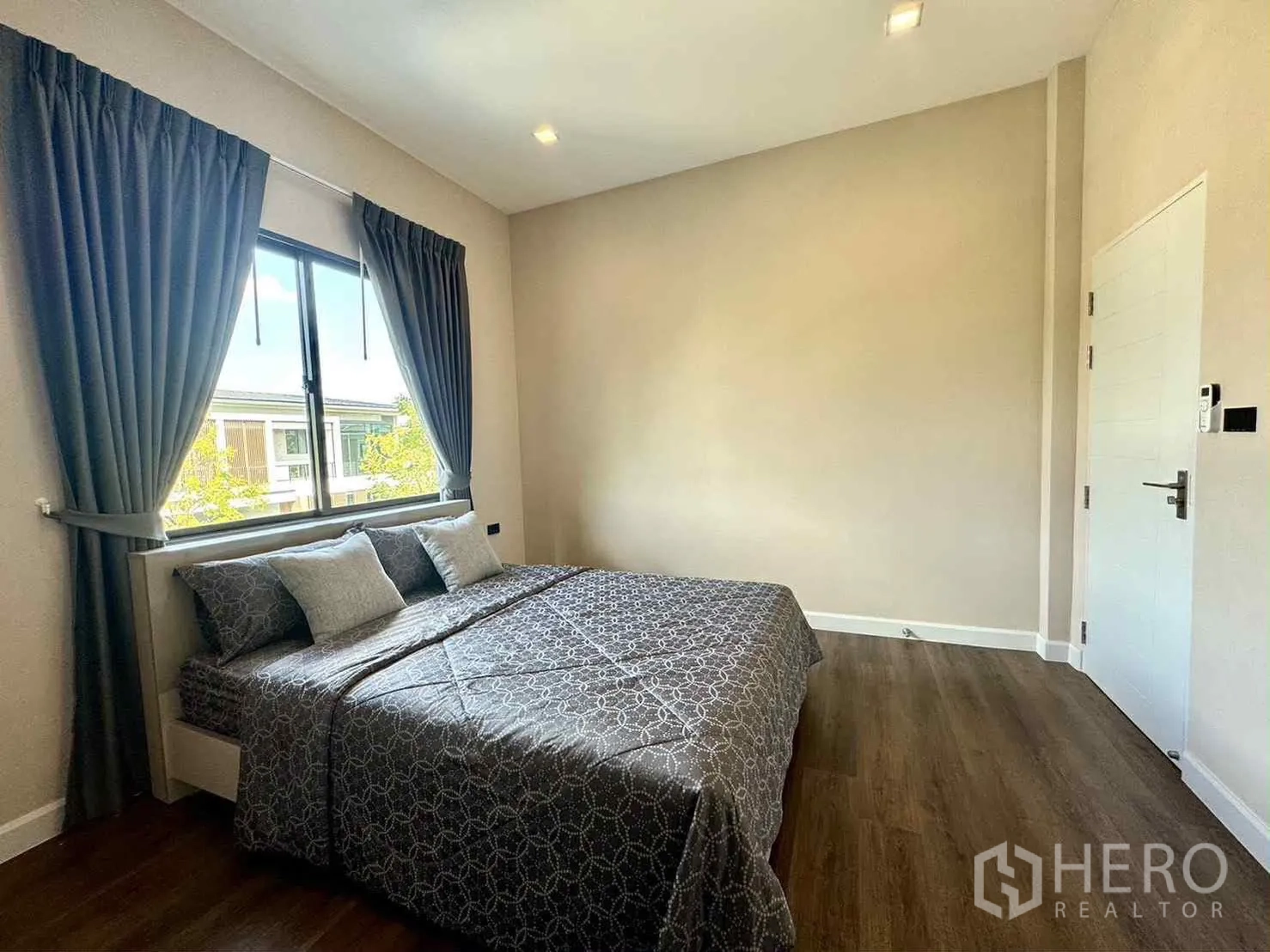 Detached House for rent in Bang Phli, Samut Prakan - Bright bedroom with double bed, wood flooring and curtained window.