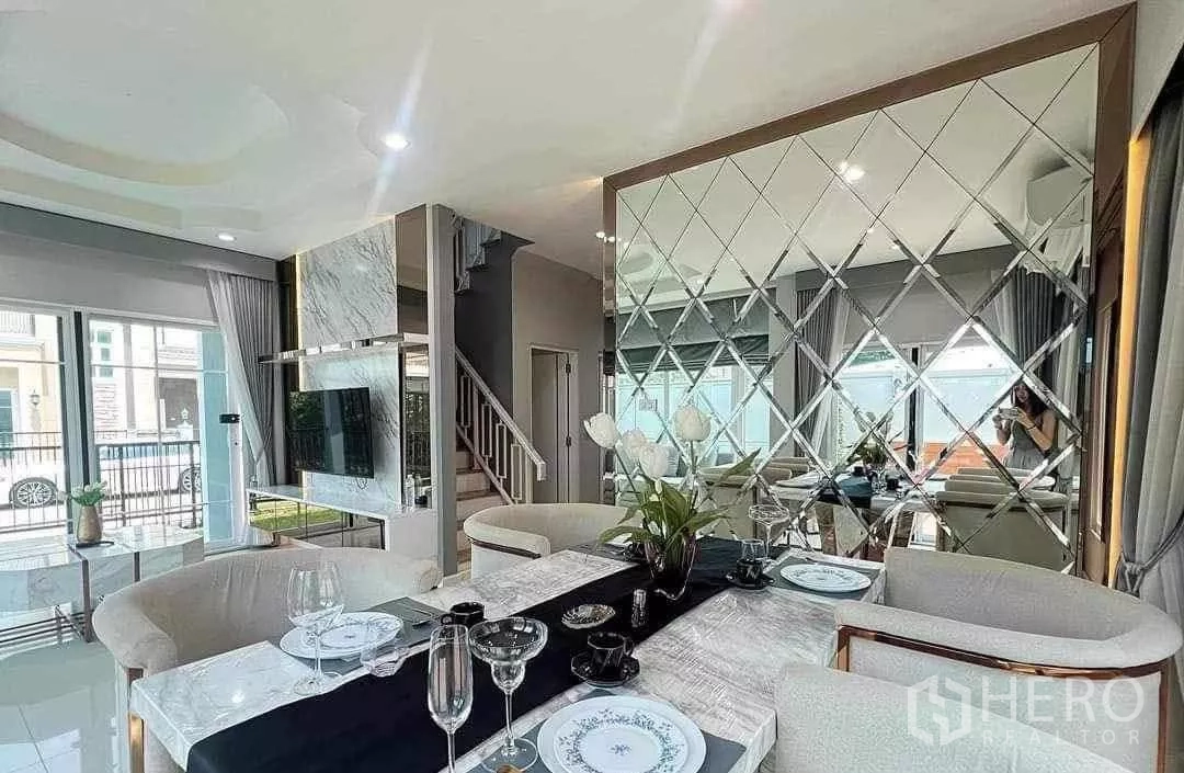 独立式住宅 出租在Bang Khen, Bangkok - 客餐厅一体空间，石纹电视墙、大窗户与菱形镜面装饰。