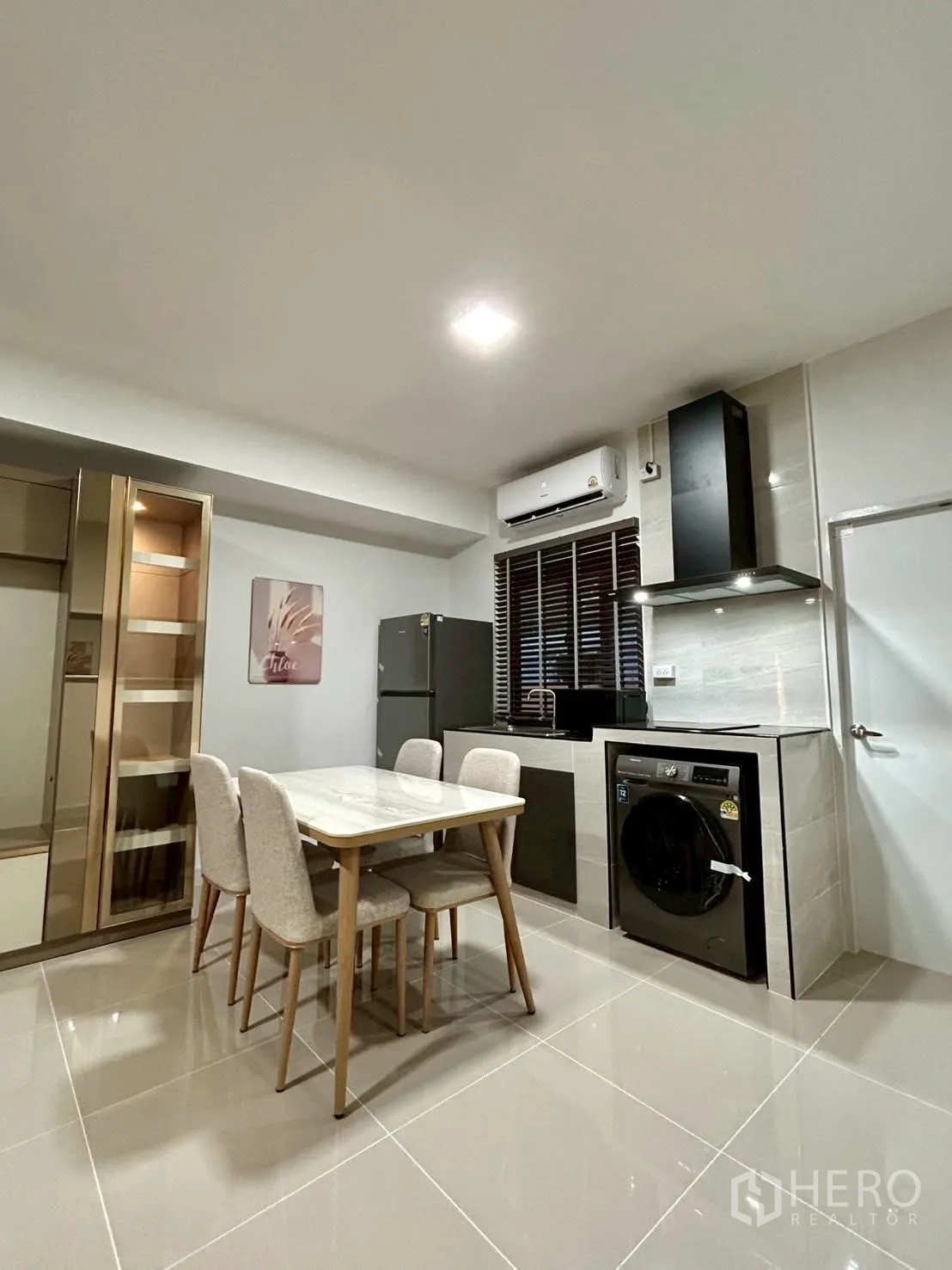 Townhouse for rent in Bang Phli, Samut Prakan - Open-plan kitchen and dining area with marble-top table, fridge, range hood and washing machine.