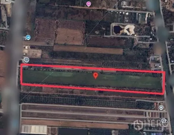 Land for sale in Bang Bua Thong, Nonthaburi - Satellite view highlighting a long rectangular land parcel outlined in red near local roads and farmland.