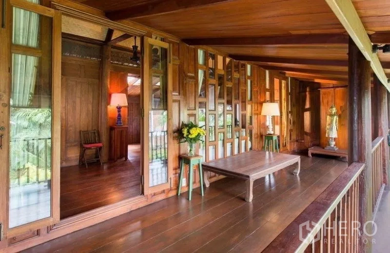 บ้าน ให้เช่าในBang Na, Bangkok - ระเบียงไม้ครอบคลุมรอบบ้าน ประตูกระจก และโต๊ะเตี้ย มองเห็นต้นไม้ร่มรื่น