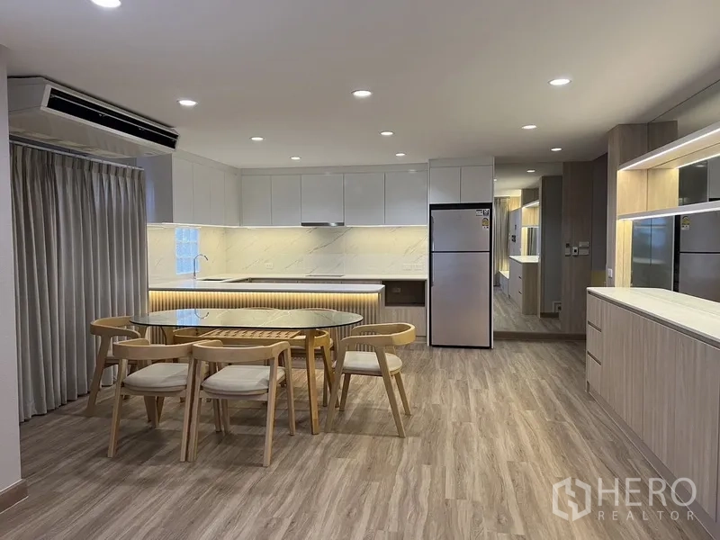 บ้าน ให้เช่าในBang Rak, Bangkok - ครัวเปิดโล่งตู้บิลท์อินผิวเงา ไฟใต้ตู้ และชุดโต๊ะอาหารบนพื้นไม้