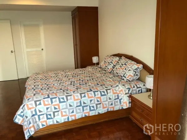 Condominium for rent or sale in Sathon, Bangkok - Spacious bedroom from another angle showing wardrobes, bedside tables and white doors.