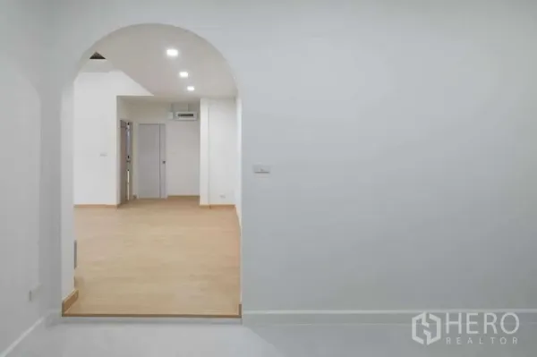 独立式住宅 出售在Bueng Kum, Bangkok - 通过拱门望向明亮客厅，木地板与筒灯照明