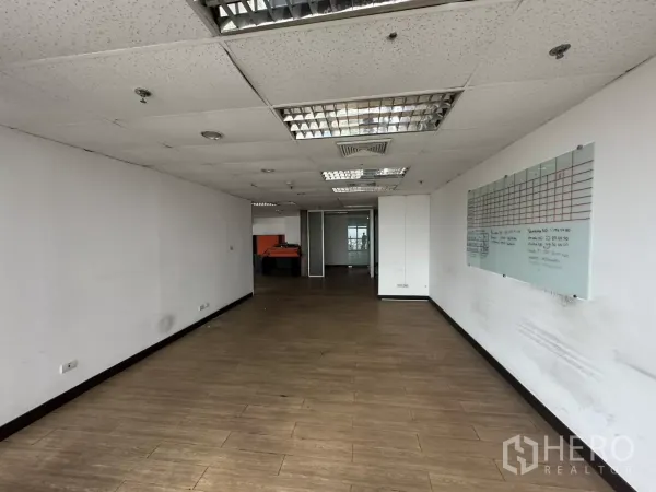 Office Space for rent in Watthana, Bangkok - Enclosed office area with wood-look floors, dropped ceiling with fluorescent lights, and a wall-mounted planning board.