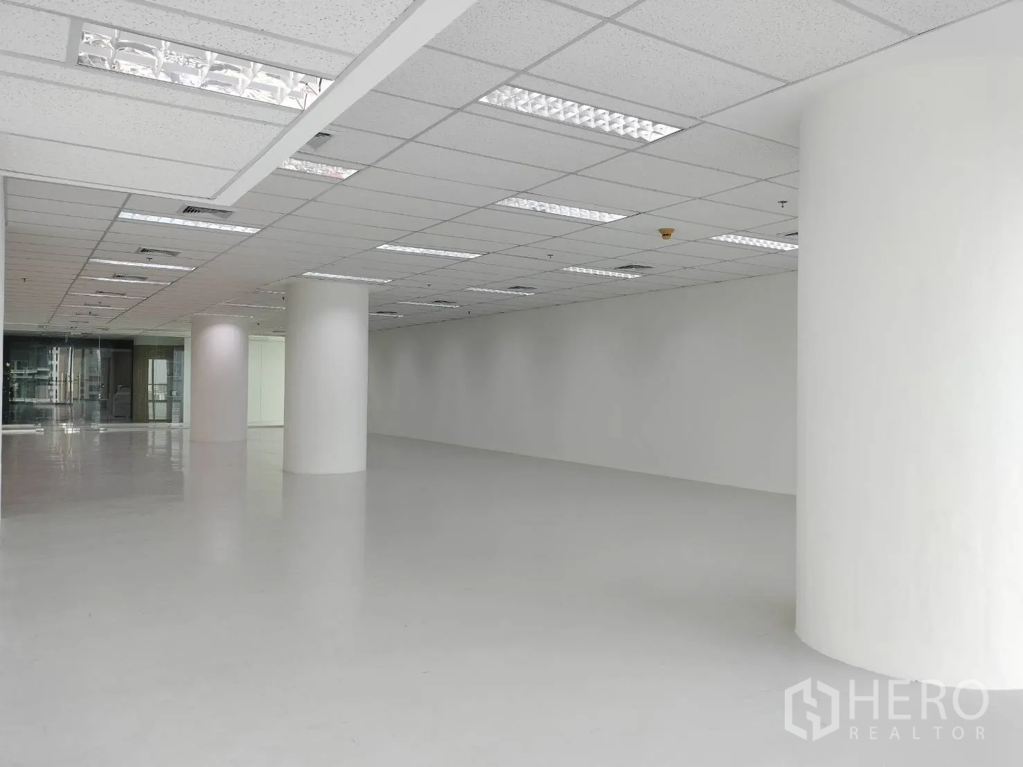 Retail Space for rent in Sathon, Bangkok - Spacious white interior with round columns and grid ceiling lighting facing glass partitions.
