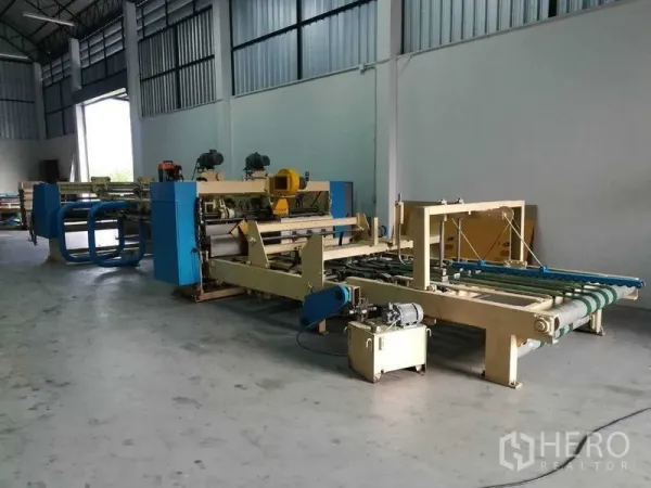 Factory for sale in Bang Len, Nakhon Pathom - Open factory floor with large machines and a wide loading door for access.